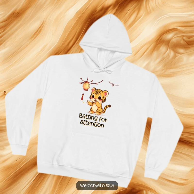Funny Tiger Cub Hoodie: A curious tiger cub bats playfully at a dangling lantern, creating a scene of cozy mischief.
